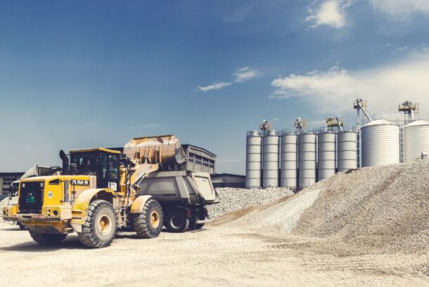 yellow wheel loader at a construction site with gravel pile and silos