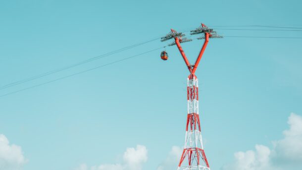 cable car passing a tall, red and white tower